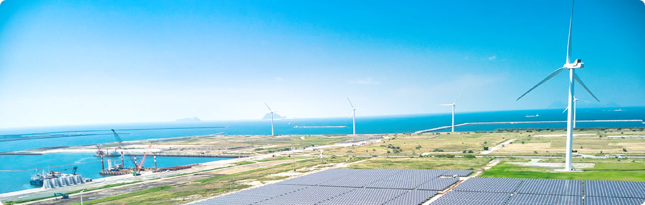 風力タービンと太陽光パネルのある海岸風景