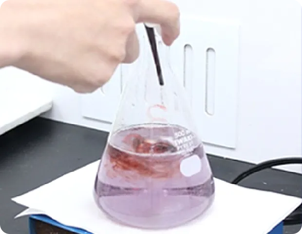 化学フラスコで液体をかき混ぜる手。