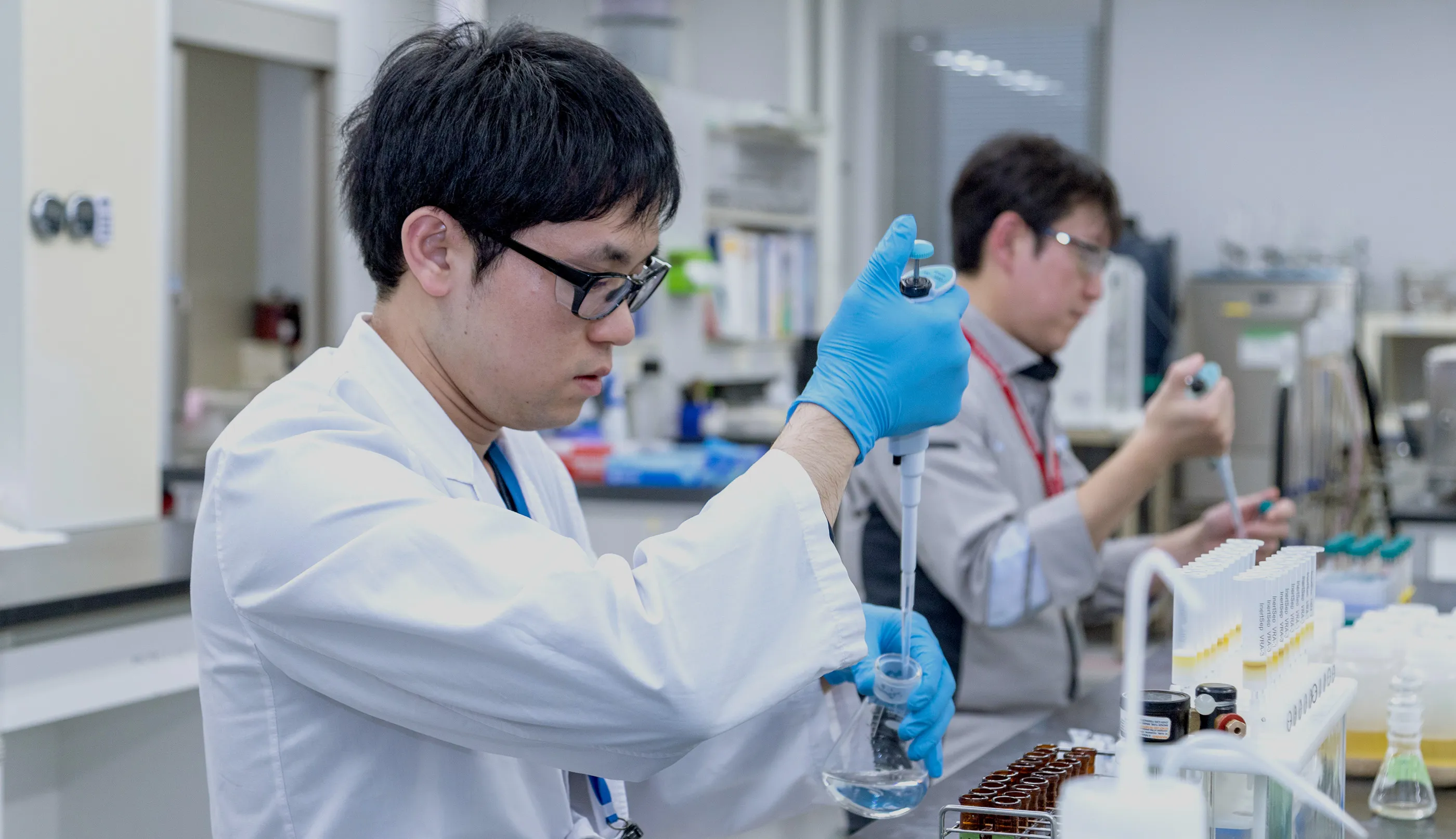 研究者ががスポイトで液体を調査する様子